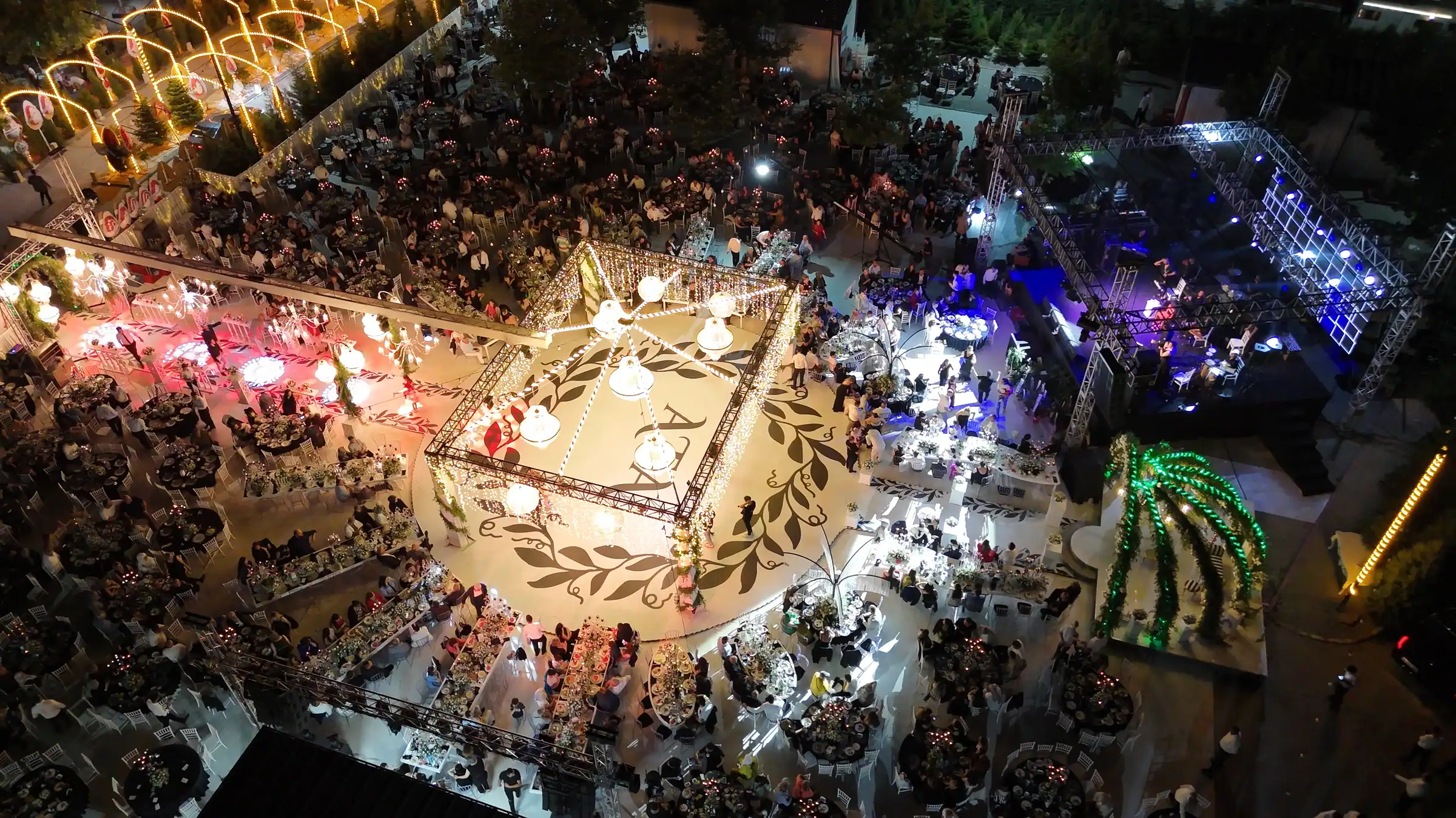 Gece kuşbakışı sünnet organizasyonu; desenli podyum, canlı müzik sahnesi ve ışıklı ağaç